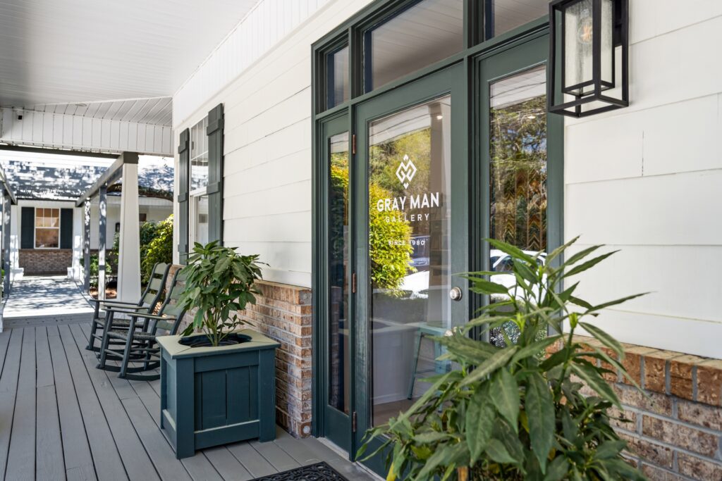 Gray Man Gallery entrance with black-framed glass door and potted plants