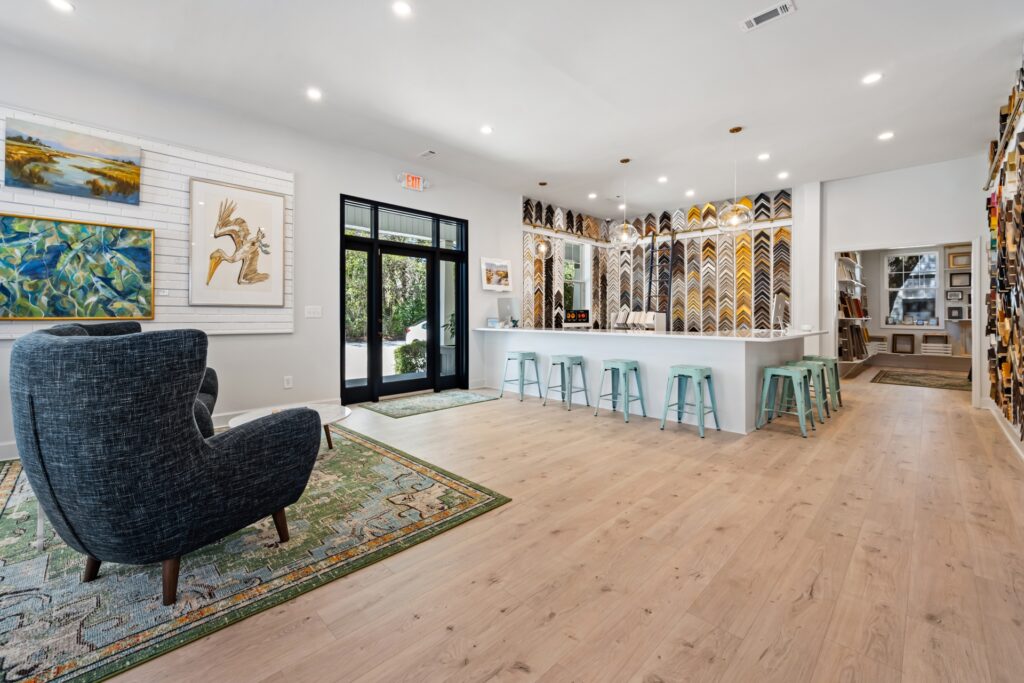 Gray Man Gallery reception counter with bar stools, black-framed doors and light wood flooring by J&S Flooring