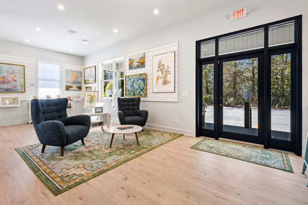Gray Man Gallery seating area with black chairs, gallery wall and green patterned rug