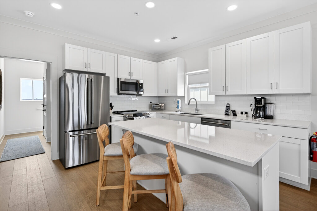 Winyah Bay Club kitchen with stainless appliances, white cabinets and wood bar stools