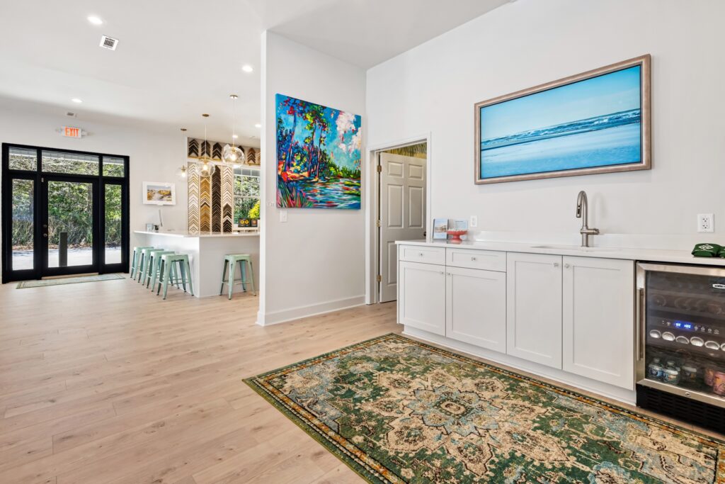 Gray Man Gallery with ocean mural, white cabinets and light wood flooring