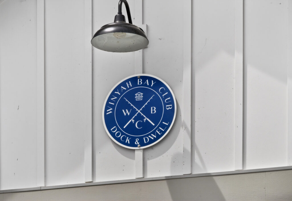 Winyah Bay Club round blue emblem on white siding