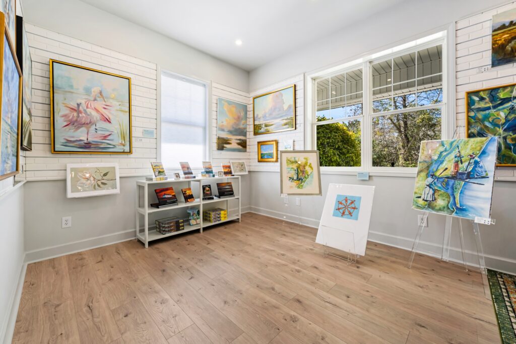 Gray Man Gallery room with framed art, display shelves and light wood plank flooring, flooring by J&S Flooring