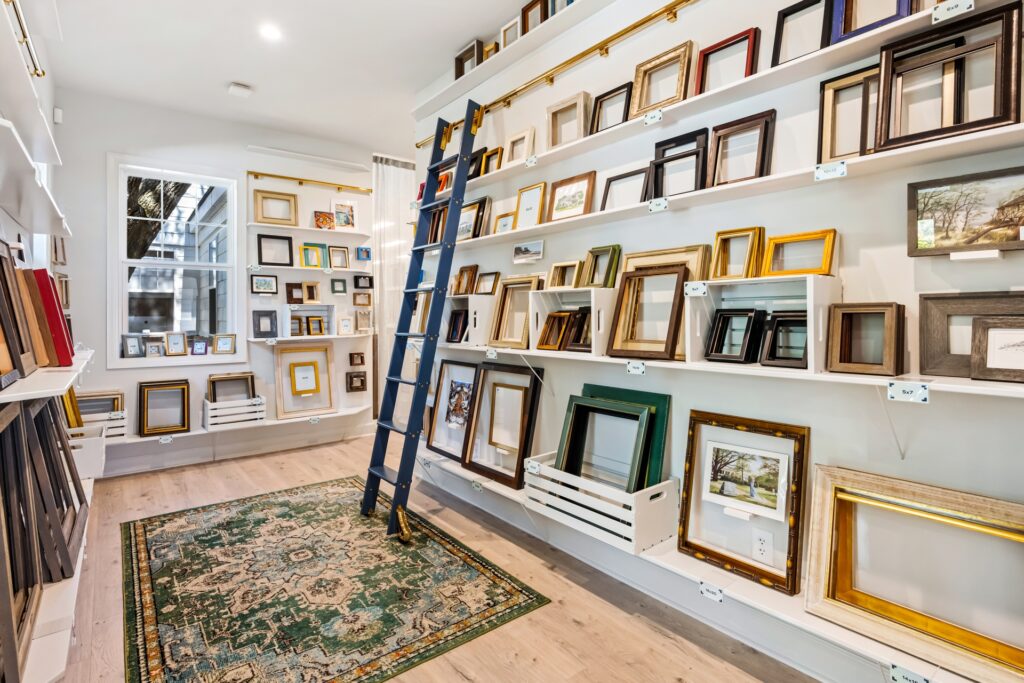Gray Man Gallery wall of framed prints with rolling ladder and light wood flooring