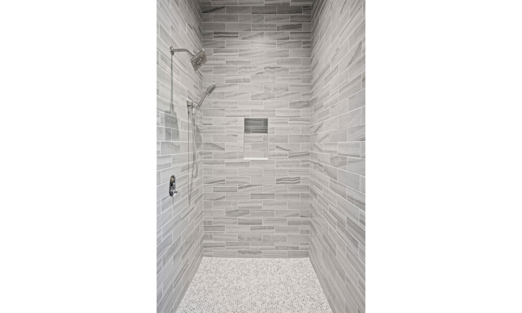 Walk-in shower with gray linear stone-look tile and recessed niche