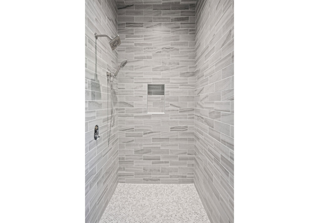 Collins Meadows walk-in shower with gray linear tile and recessed niche