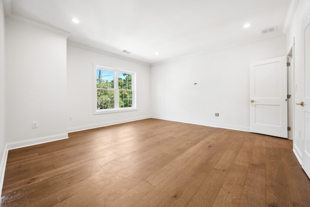 Collins Meadows empty room with light wood flooring and window, flooring by J&S Flooring in Georgetown, SC