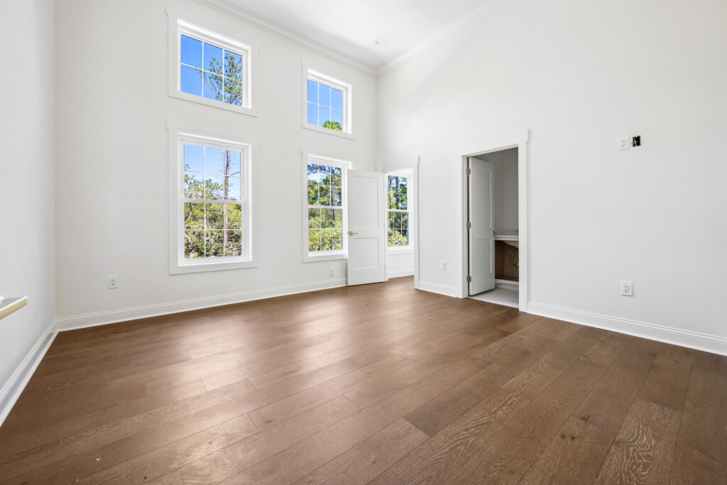 Collins Meadows empty room with wood plank flooring, windows and open doorway