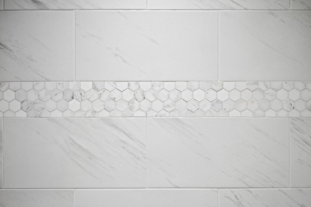 Collins Meadows shower wall with hexagon tile accent band on large-format marble-look tile