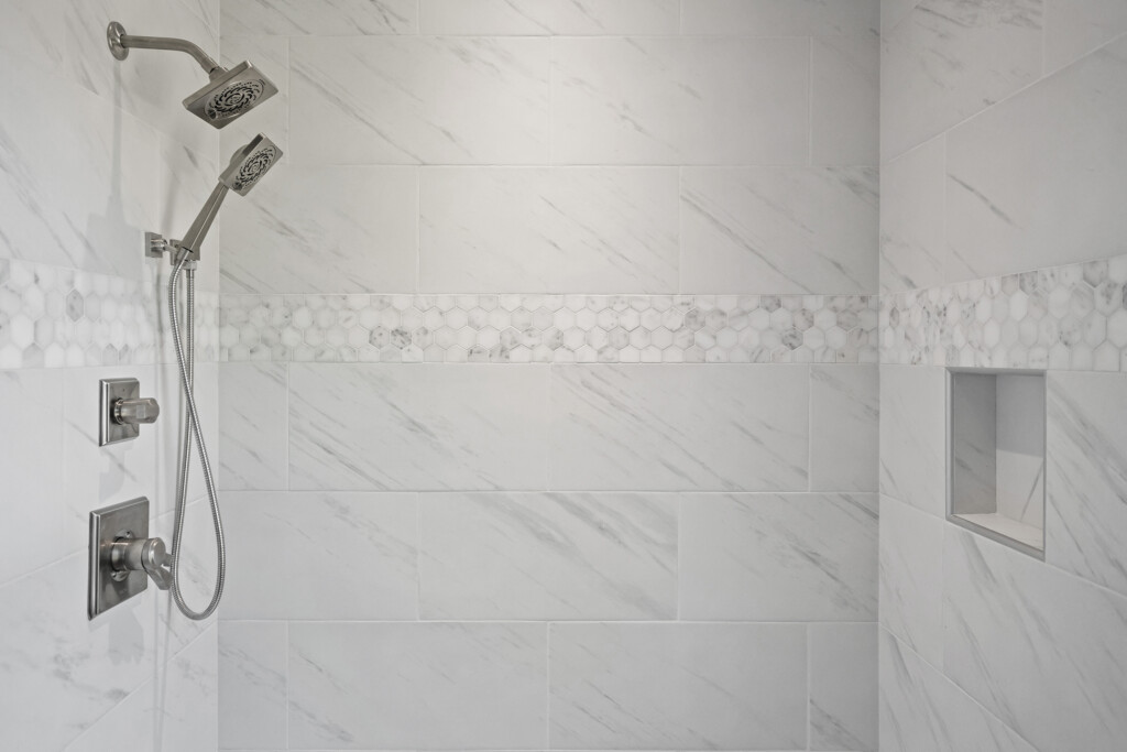Collins Meadows large-format marble-look shower tile with hexagon accent band
