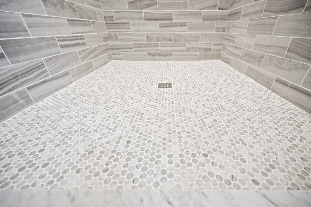 Collins Meadows shower with hexagon mosaic floor tile and linear tile wall
