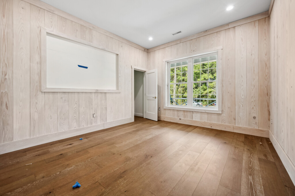 Collins Meadows room with whitewashed wood plank wall and wood flooring