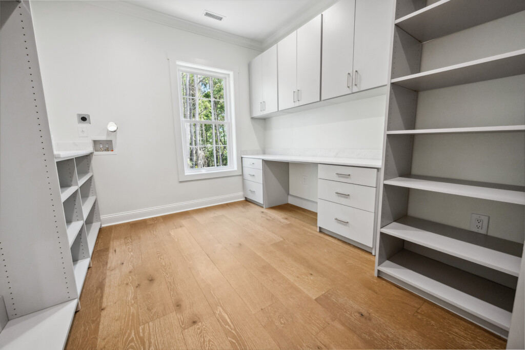 Collins Meadows home office with built-in desk, cabinets and wood flooring