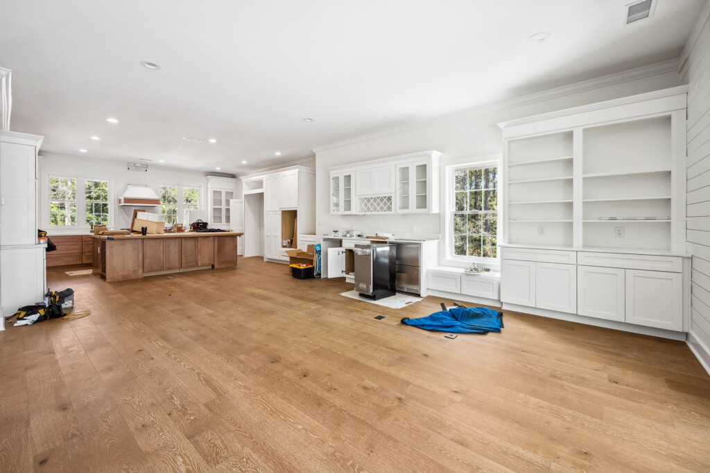 Collins Meadows kitchen under construction with white cabinets and wood flooring