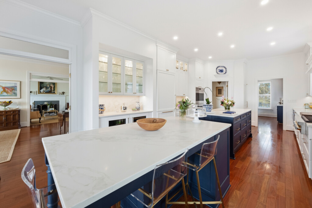 Colony Point kitchen island with wooden bowl and white cabinetry over warm hardwood flooring, by J&S Flooring
