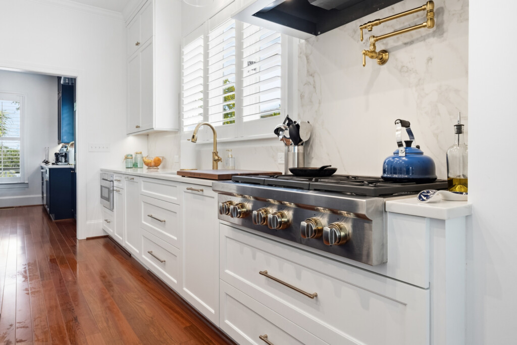Colony Point kitchen with professional range, white cabinets and brass faucet