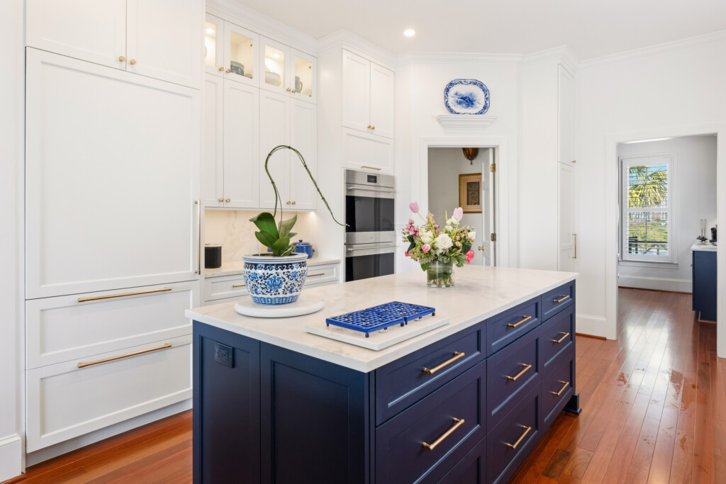 Colony Point kitchen island with navy base, double wall ovens and fresh flowers