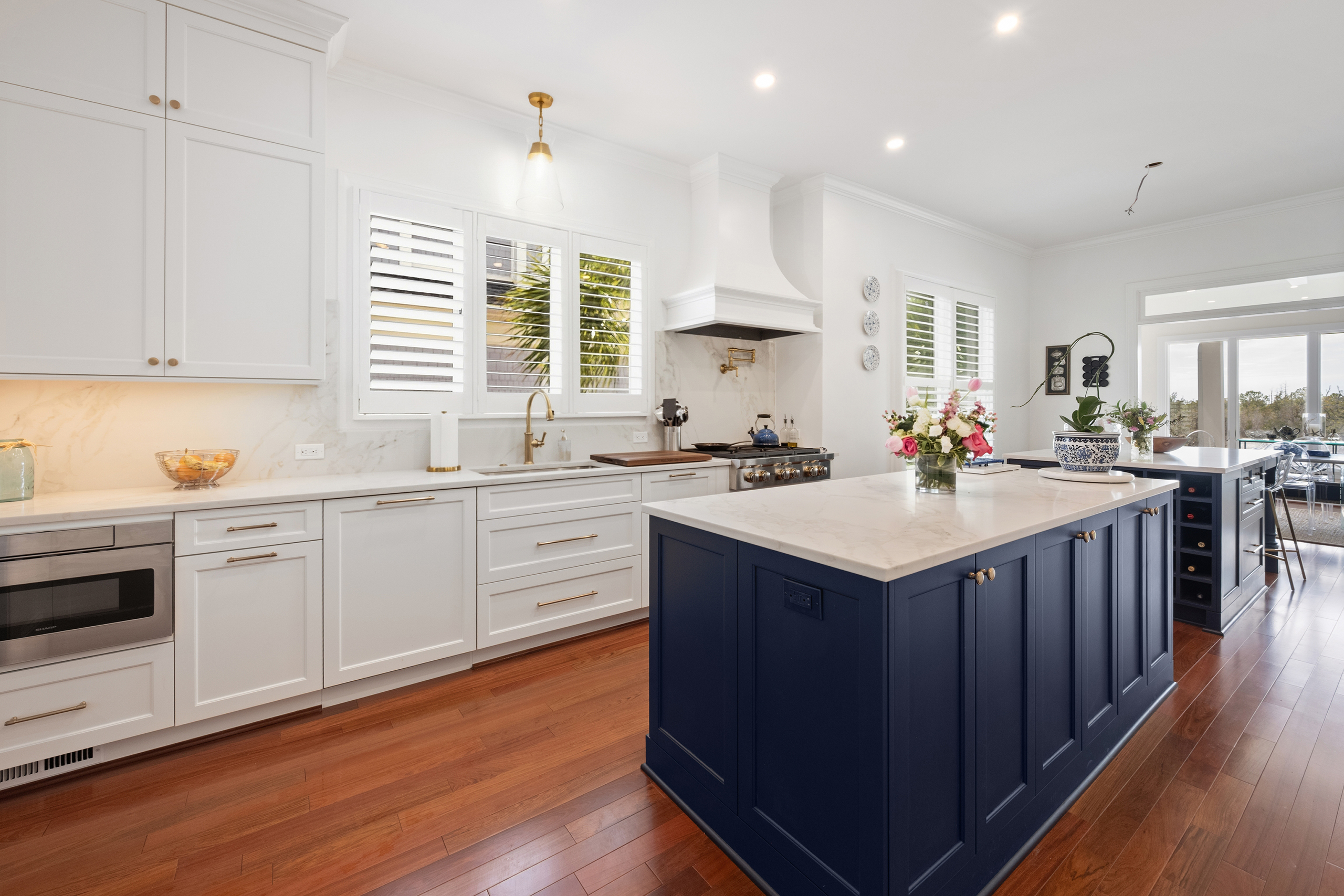 Colony Point kitchen with plantation shutters, range hood and navy island