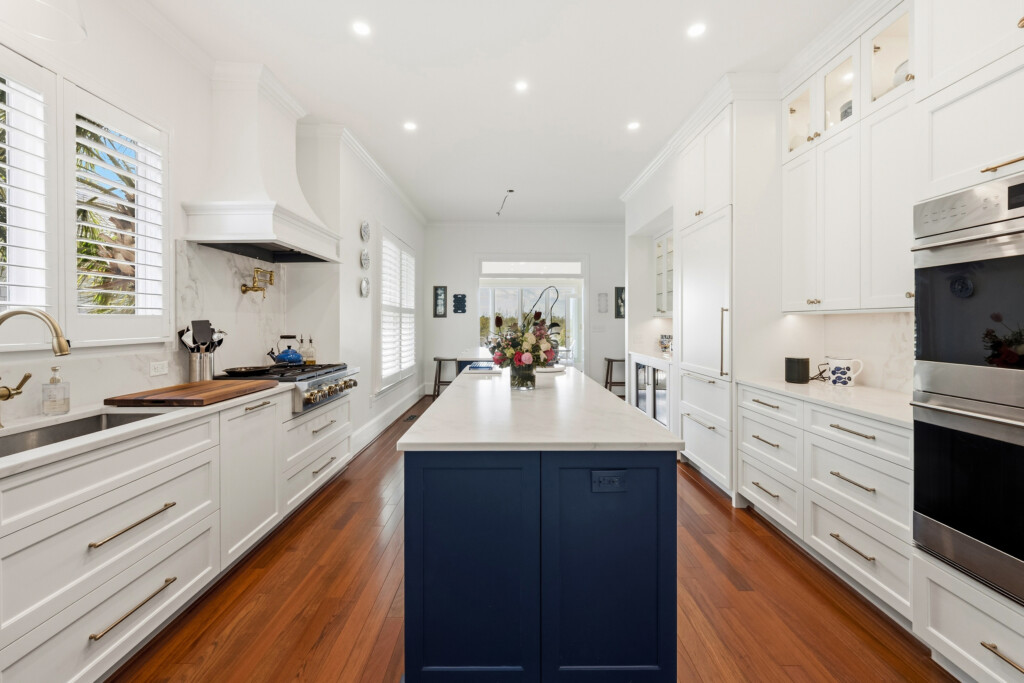 Colony Point kitchen with navy island, white cabinetry and hardwood flooring by J&S Flooring