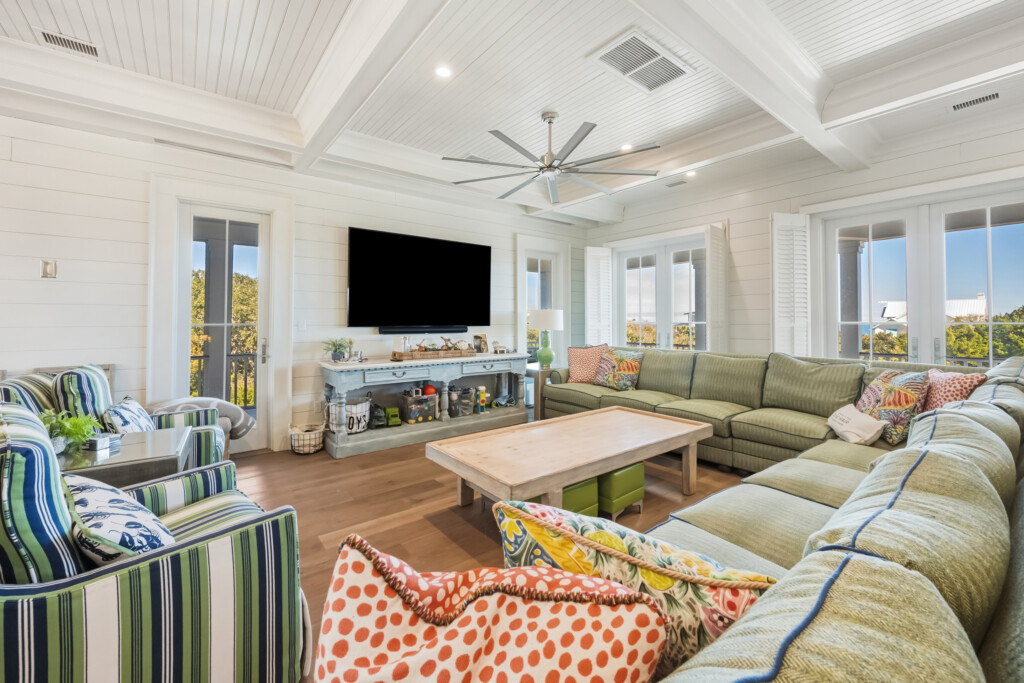 DeBordieu living room with green sectional and wall-mounted TV, wood flooring by J&S Flooring in Georgetown, SC