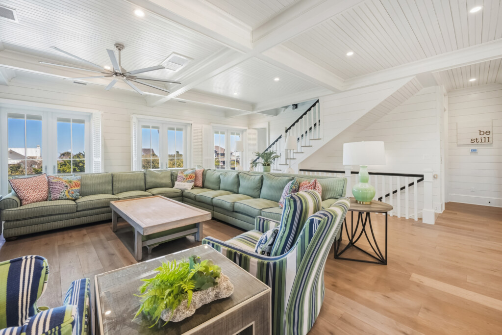 DeBordieu living room with green sectional sofa, open staircase and wood flooring