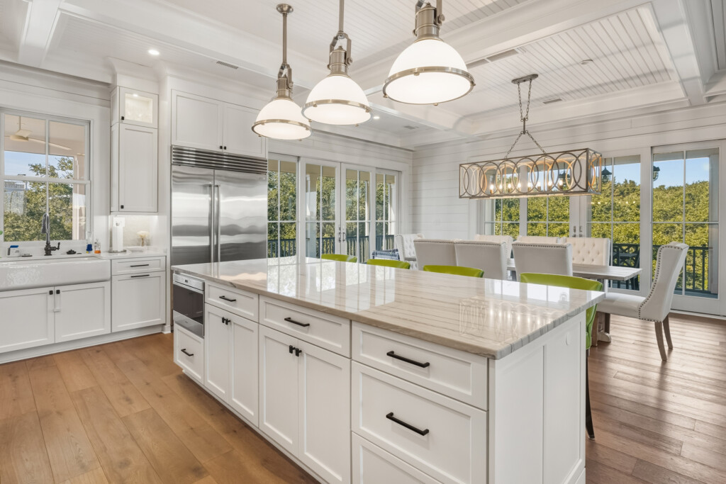 DeBordieu kitchen island with white cabinets, quartz countertop and pendant lighting