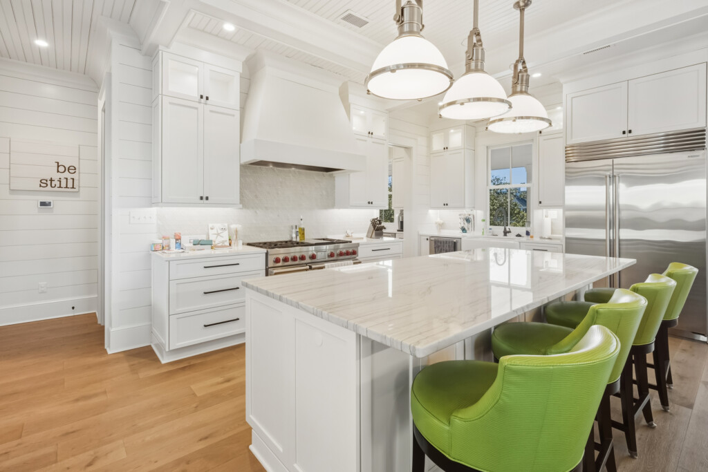 DeBordieu kitchen with large quartz island and range hood, wood flooring by J&S Flooring