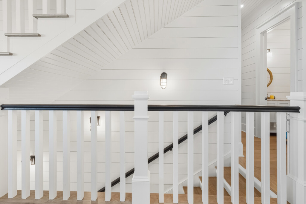 DeBordieu upstairs hallway with shiplap walls and black-and-white stair railing