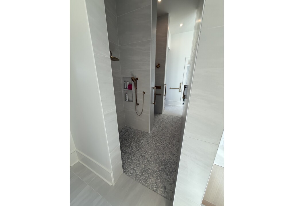 Woodward Project shower with pebble tile floor seen from the hallway