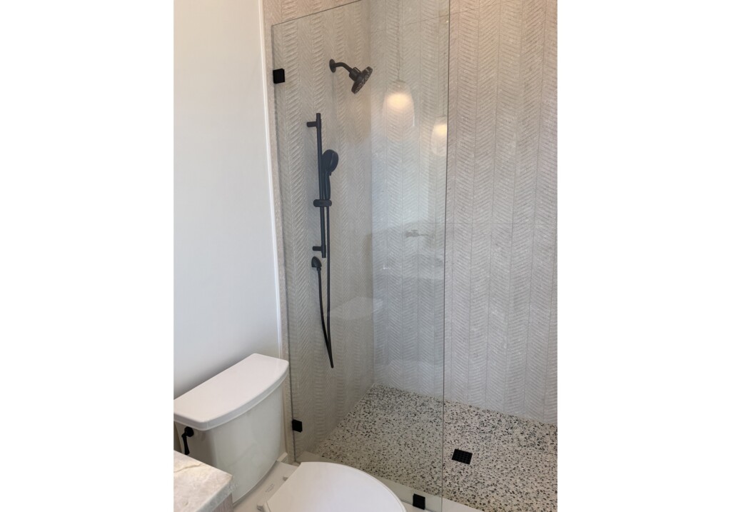 Woodward Project shower with black rain shower fixture and large-format tile