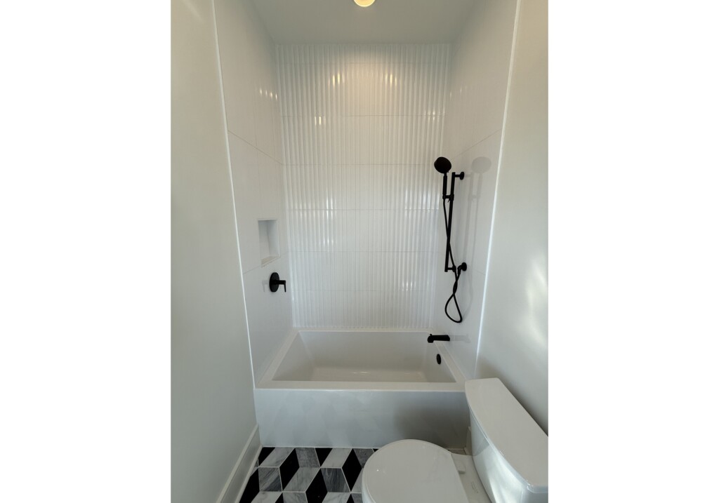 Woodward Project tub and shower with white wall tile and black fixtures