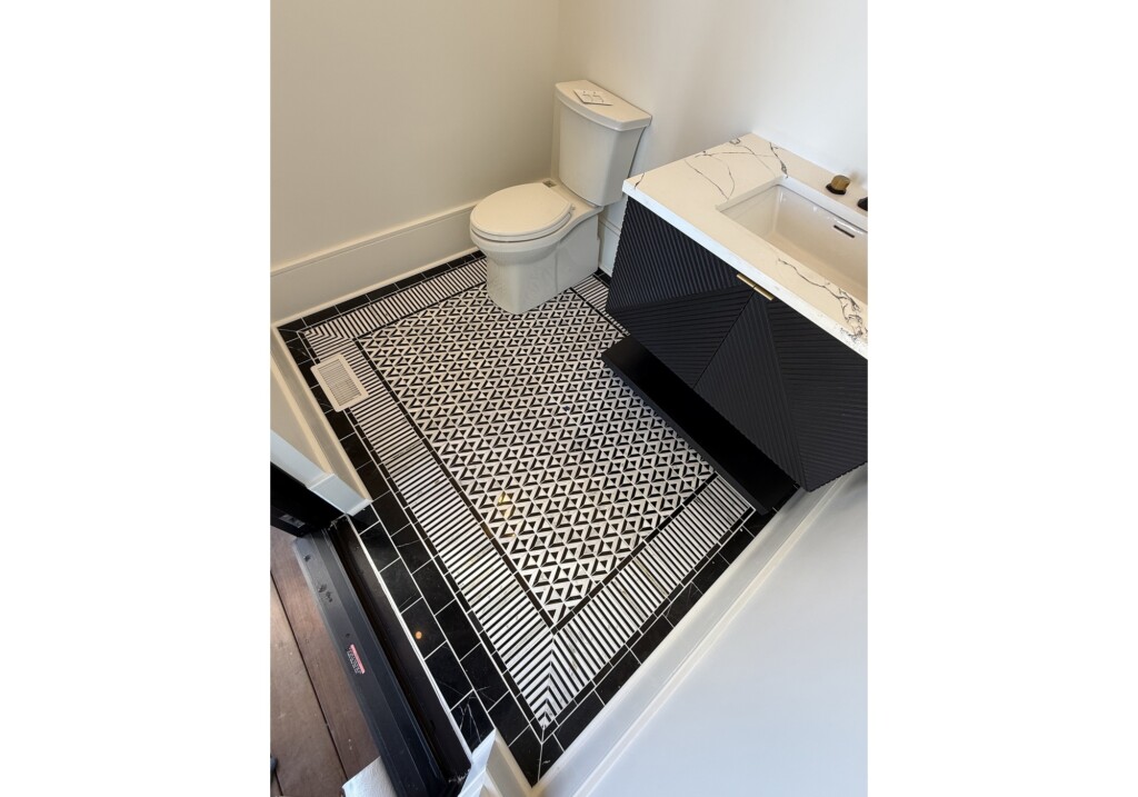 Woodward Project bathroom with black-and-white patterned mosaic floor tile and navy vanity, tile by J&S Flooring