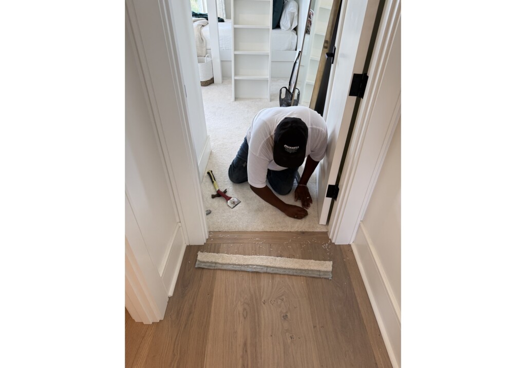 J&S Flooring installer laying wood plank flooring in a doorway at Woodward Project in Georgetown, SC