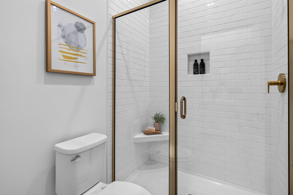 Walk-in shower with white subway tile and brass-framed glass door