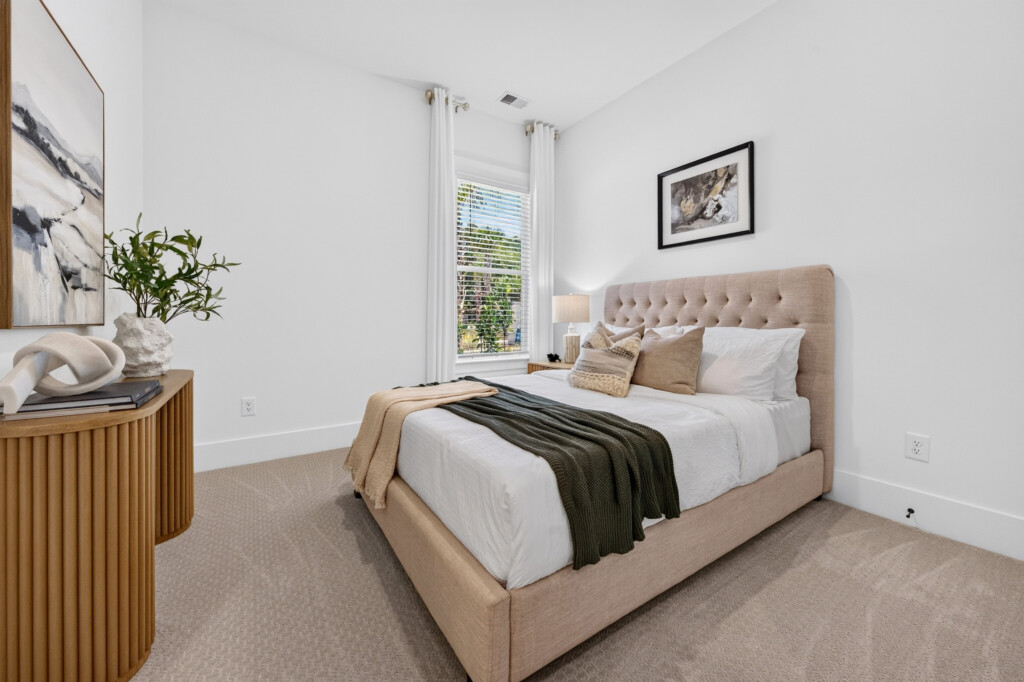 Bedroom with tufted headboard and neutral carpet