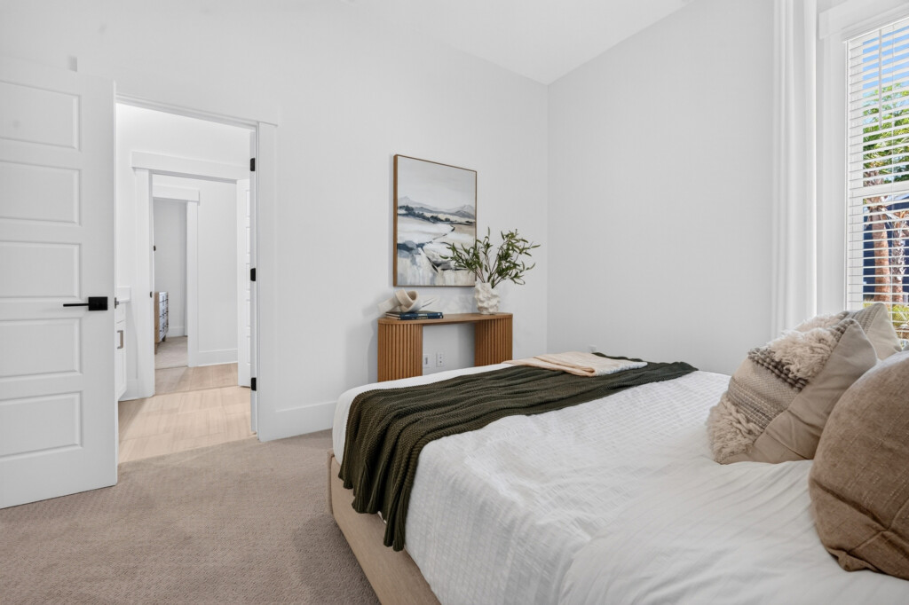 Bedroom with neutral carpet and view into the hallway