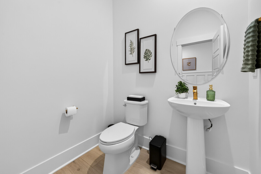 Powder room with pedestal sink and light wood-look plank flooring