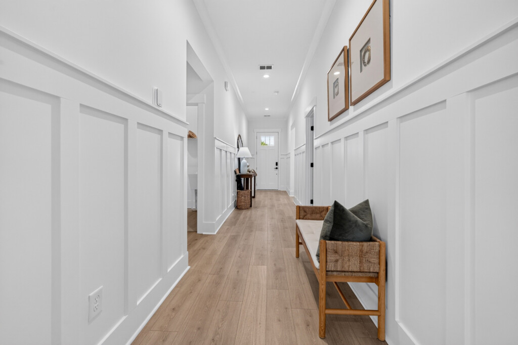 Hallway with wainscoting and light wood-look plank flooring