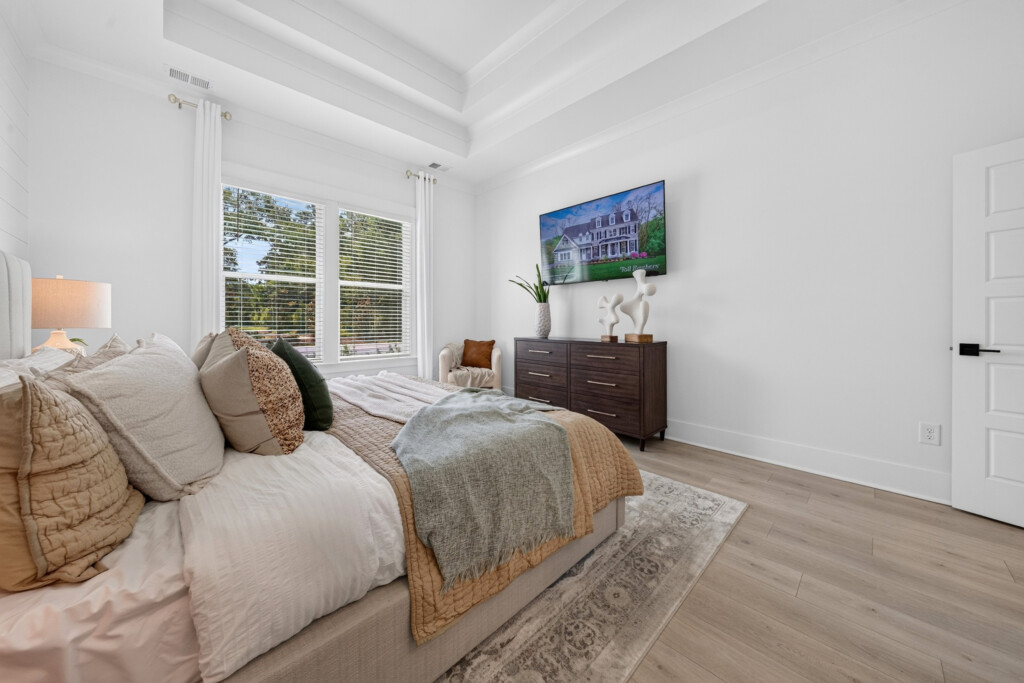 Bedroom with tray ceiling and light wood-look plank flooring