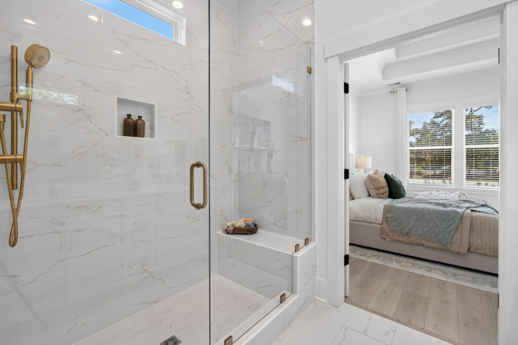 Glass walk-in shower with marble-look porcelain tile and brass fixtures