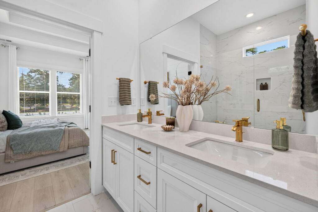 Bathroom vanity with marble-look tile and view into the bedroom