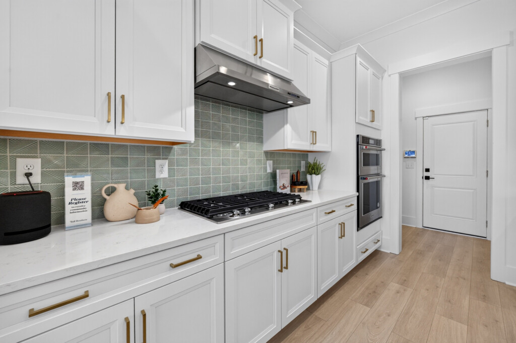 Kitchen with green tile backsplash and light wood-look plank flooring