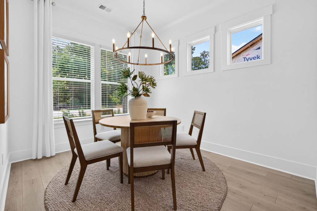 Dining nook with round table, chandelier, and light wood-look plank flooring