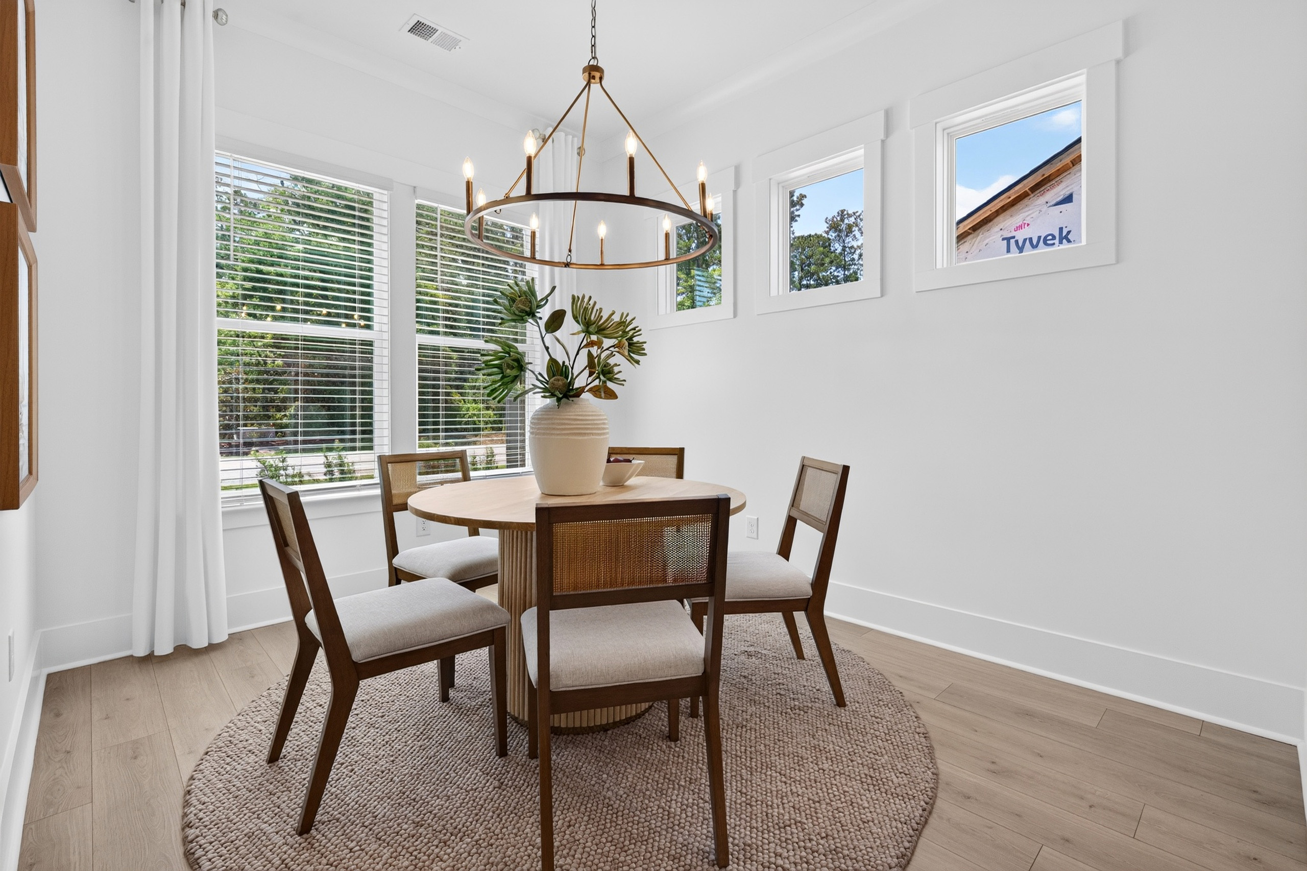 Dining nook with round table, chandelier, and light wood-look plank flooring