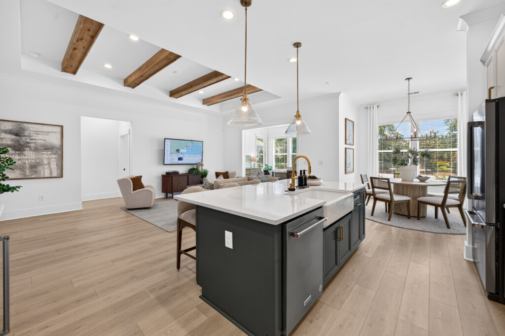 Open-concept kitchen and living area in a Sanderling Bay home with light wood-look plank flooring