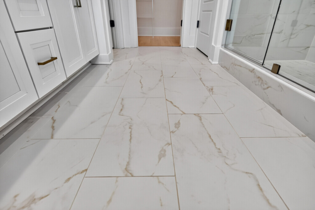 Bathroom floor with large-format marble-look porcelain tile in a Sanderling Bay home