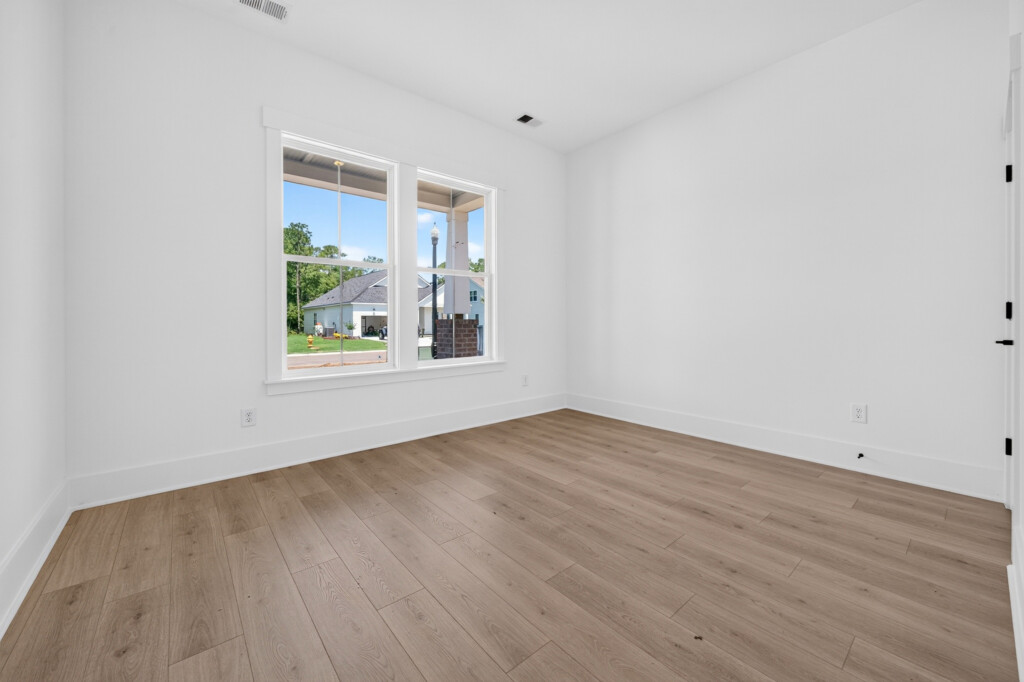 Empty bedroom with light wood-look plank flooring in a new Sanderling Bay home