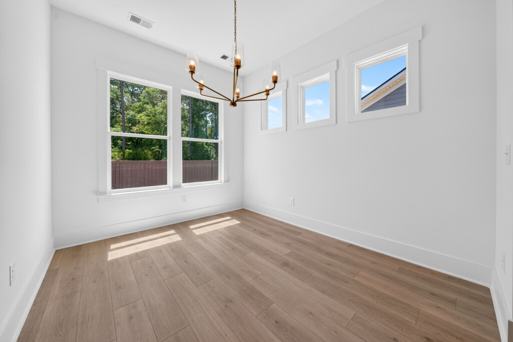 Empty dining area with chandelier and light wood-look plank flooring
