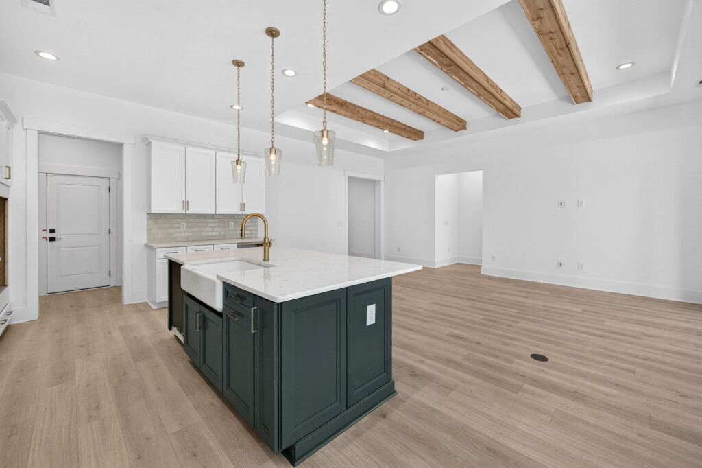 Dark kitchen island under wood beams with light plank flooring