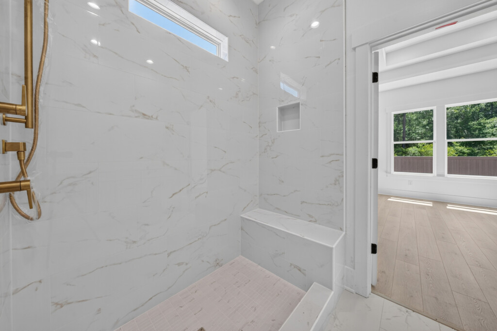 Walk-in shower with marble-look tile opening to the bedroom